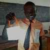School boy holding a lantern lighting up a classroom.