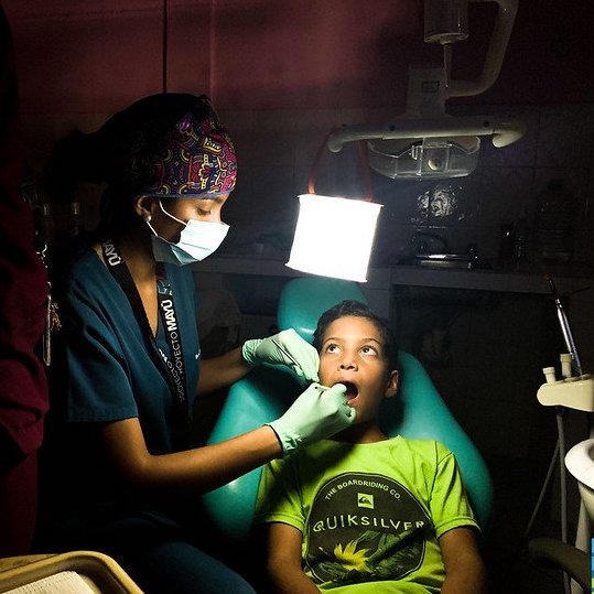 Dentist using a luminaid light to help take care of a child.
